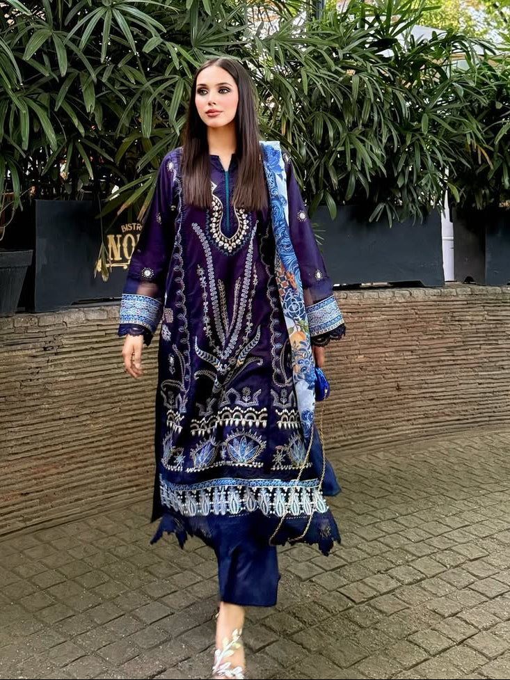 Woman in a patterned dress standing outdoors with greenery in the background